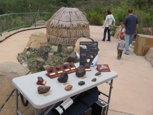 Cool table full of meteorites next to traditional Kumeyaay house made of willow branches.