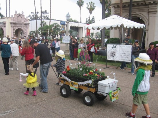 The parade approaches the reflecting pool as it passes booths lining El Prado.