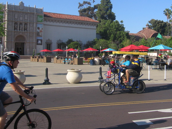 Bicyclist and tourists on a rented quadracycle head through the beautified Plaza de Panama.