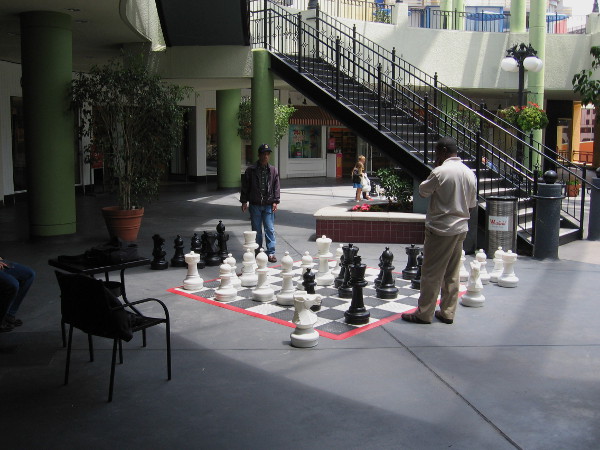 People enjoy a leisurely game of chess with gigantic chessboard and pieces at Horton Plaza.
