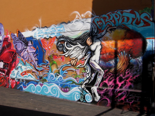 Graffiti lady dances on wall bordering tiny parking lot, across from Tabletop Commons in Hillcrest.