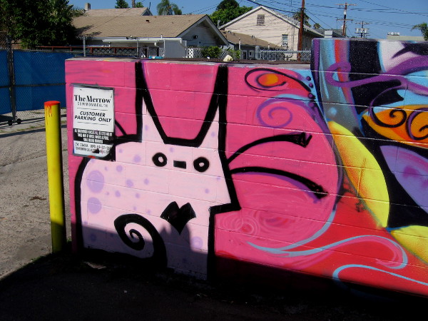 Pink abstract cat awaits at edge of Hillcrest alley.