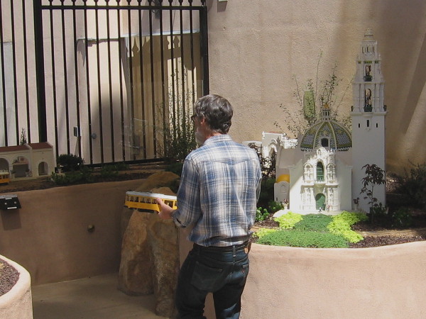 Volunteer at San Diego Model Railroad Museum walks past 3D-printed model of the historic California Building with its bell tower.