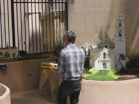 Volunteer at San Diego Model Railroad Museum walks past 3D-printed model of the historic California Building with its bell tower.