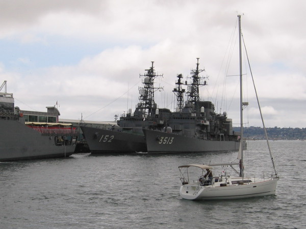A sailboat on San Diego Bay checks out an unusual sight on a cloudy day.