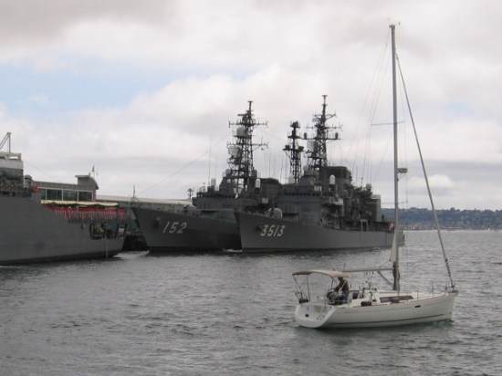 A sailboat on San Diego Bay checks out an unusual sight on a cloudy day.