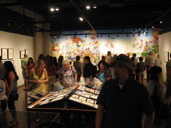 Visitors check out original comic book art created for Comic-Con souvenir program books over the past 45 years.