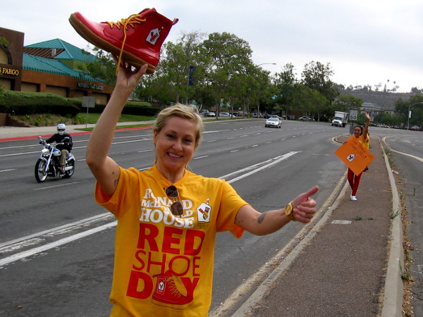Volunteer at a Mission Valley intersection lifts a red shoe and gives a thumbs up! She was raising money for Ronald McDonald House today!