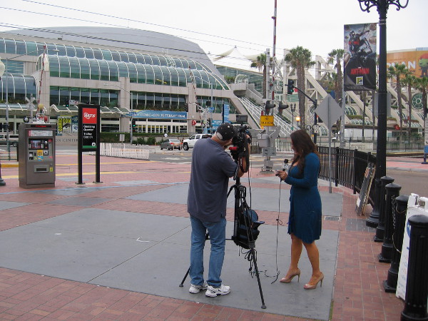 A local television news reporter stands near entrance to the Gaslamp, previewing 2015 Comic-Con on camera.