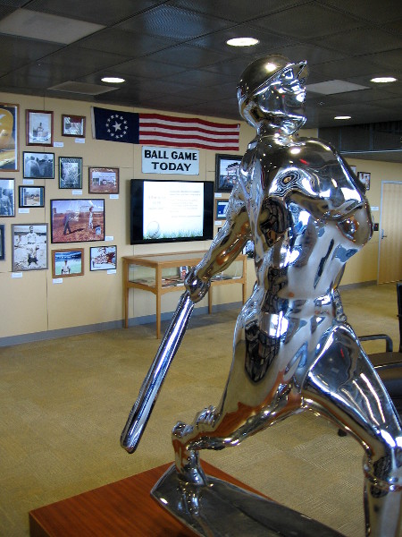 Bronze and chrome Yoram Wolberger statue of a baseball player swinging a bat.