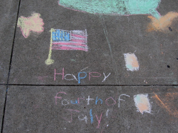Someone wrote on the sidewalk with chalk: Happy Fourth of July!
