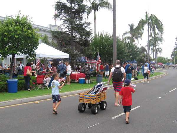Kids with flags follow a big wagon full of lawn chairs, as the parade is almost ready to start.