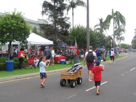 Kids with flags follow a big wagon full of lawn chairs, as the parade is almost ready to start.