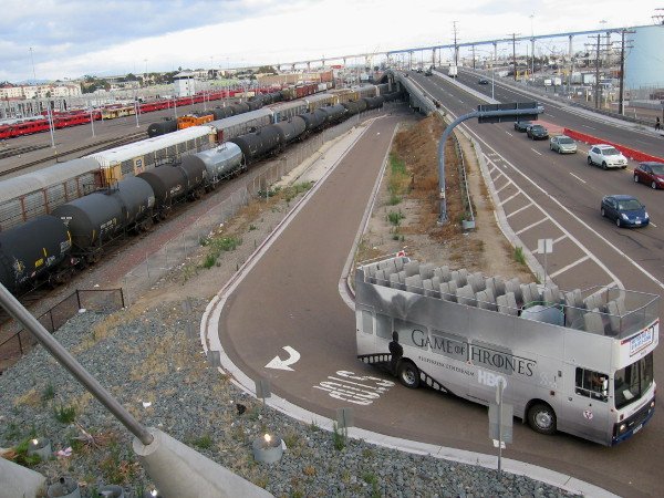 Looking down from Harbor Drive bridge at San Diego rail yard and a bus with Game of Thrones wrap turning about.