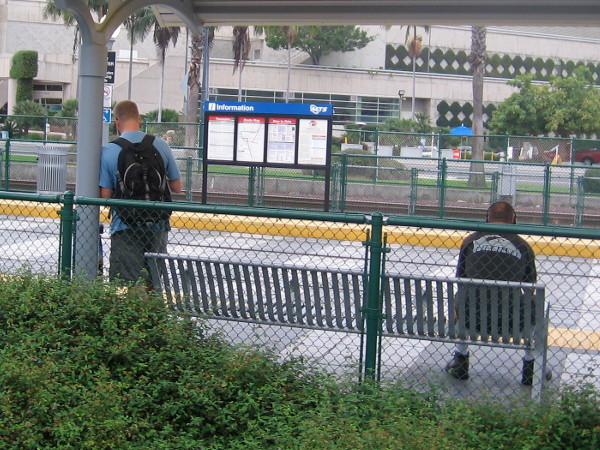 Early morning commuters await separately at the Convention Center trolley station.