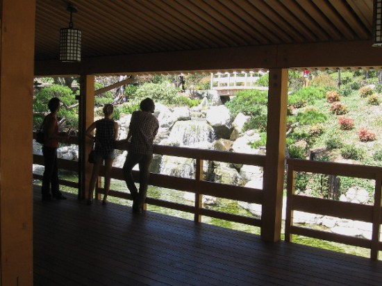 Visitors at the Japanese Friendship Garden stand in the shade of the Inamori Pavilion looking down at a very beautiful waterfall.