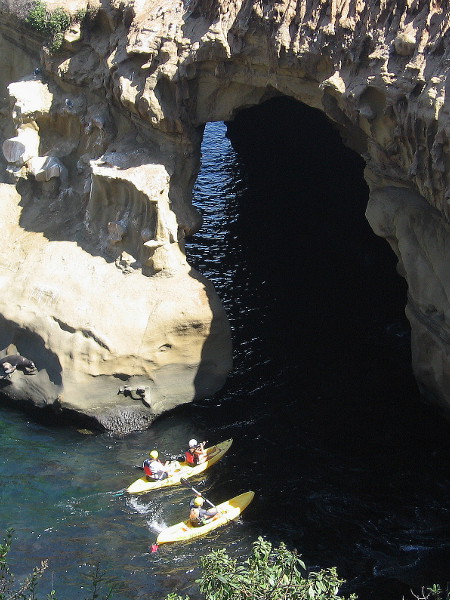 The kayakers can't resist a strong impulse to enter the cave. They turn carefully to peer into the darkness deep within the earth. There seems to be a strange blue light shimmering inside.