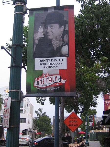 Little Italy street banner shows actor Danny DeVito enjoying a drink.