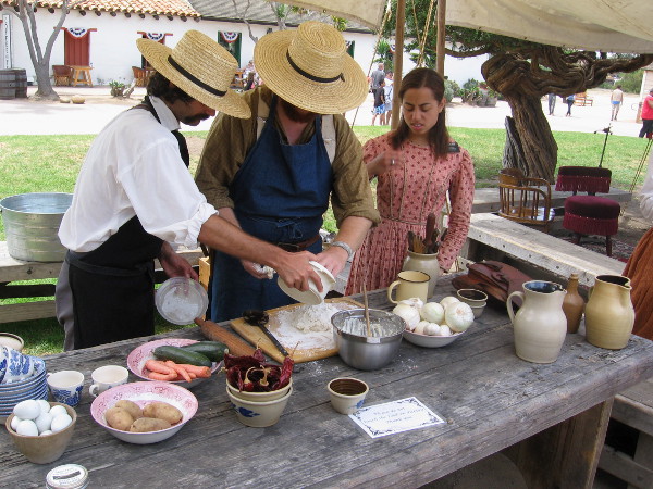These folks in historical costume are busily preparing some biscuits, a common food in the early days of San Diego.