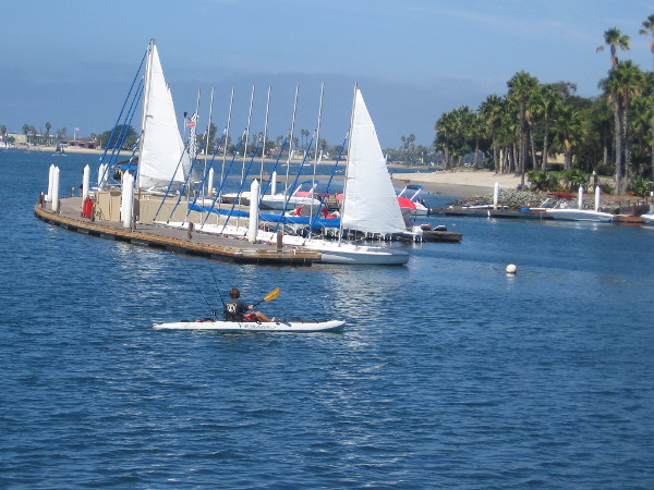 A fisherman rows a kayak near sailboats docked at Paradise Point Resort on Vacation Isle.