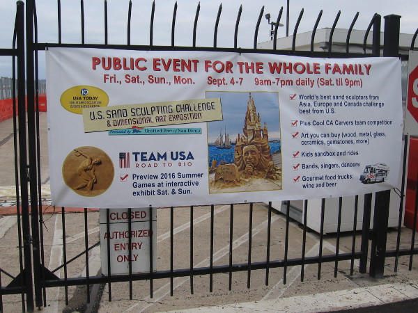 Banner on fence at B Street Pier near Cruise Ship Terminal promotes the 2015 U.S. Sand Sculpting Challenge and Dimensional Art Exposition in San Diego.