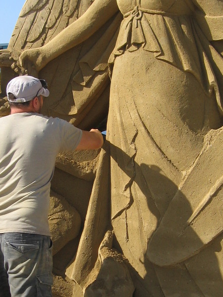 A masterpiece of sand is being created as the public watches and takes photographs.