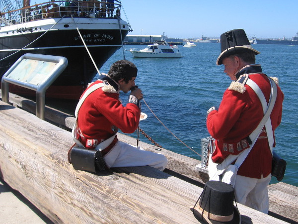 Two members of the Royal Guard enjoy a drink and snack on San Diego's Embarcadero during the Festival of Sail. They must be shore leave.