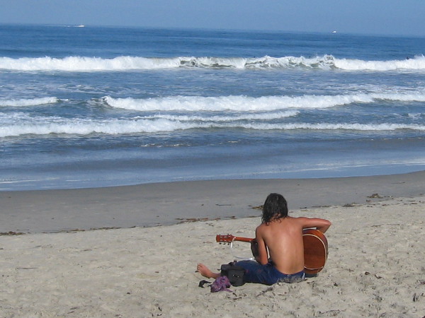 A lone guitarist performs a duet with the mighty ocean.