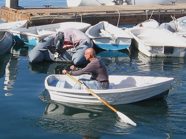Man rows boat across the water. A typical scene of life on the North Embarcadero.