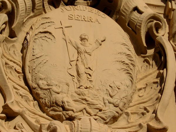 Ornamental art on Balboa Park's Casa del Prado depicts Saint Junipero Serra holding a cross among Spanish soldiers and native peoples in what today is California.