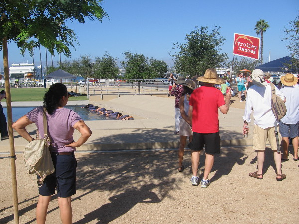 The dancers are lying in the water as everyone trickles in and finds a place to sit or stand.