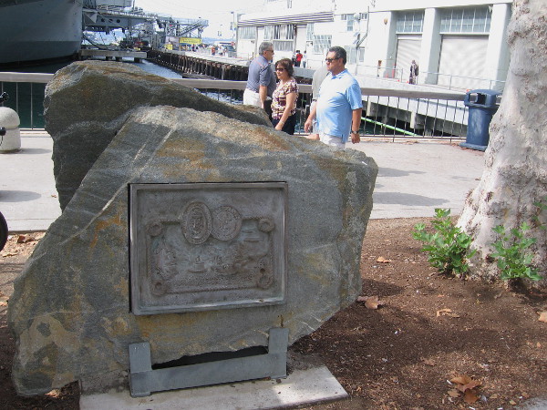 People pass the Navy Bicentennial Commemorative Plaque, displayed on San Diego's Embarcadero, on the Greatest Generation Walk near the USS Midway Museum. Photo taken October 17, 2015.