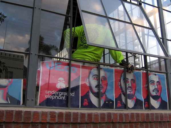 Worker inside old brick building that is being renovated. Cool posters in windows advertise Underground Elephant.