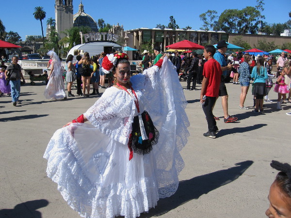 A lady, with a skull face painting, poses in a beautiful Dia de los Muertos dress. What could possibly go wrong today?