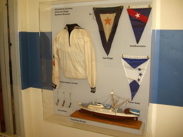 Display case contains artifacts from the San Diego Maritime Museum, including model of a tuna boat.
