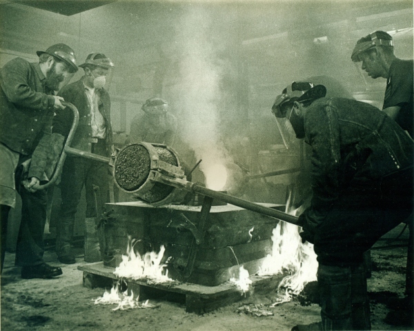 Molten bronze is poured in the foundry of the USS Ajax. Historical photograph of the Navy Bicentennial Commemorative Plaque being created. Photo credit: United States Navy.
