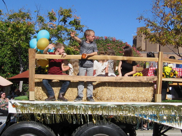 Kids wave from a float dedicated to raising awareness about childhood cancer.
