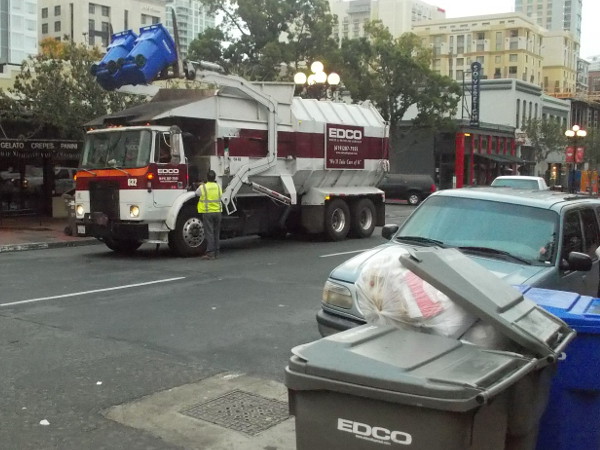 Blue recycle bins are lifted, banging and clattering, and contents are dumped.