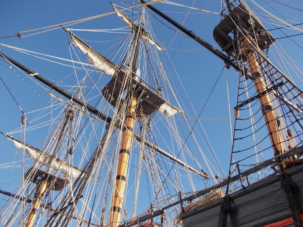 Looking upward at the three masts, furled sails and other complicated rigging.