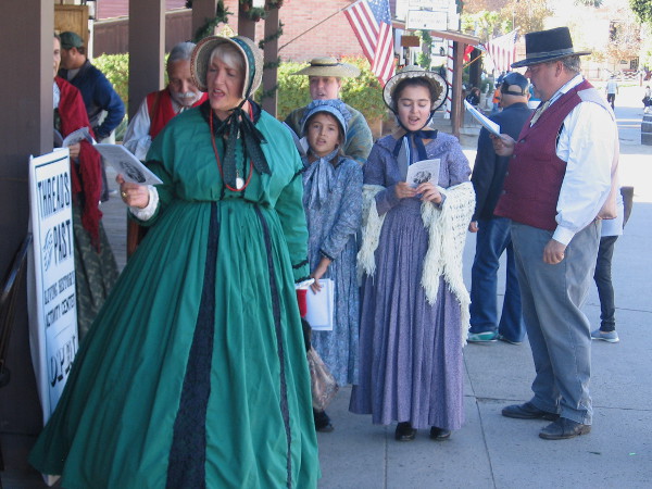 A group of old-fashioned Christmas carolers in Victorian costumes brings holiday cheer to Old Town San Diego State Historic Park.