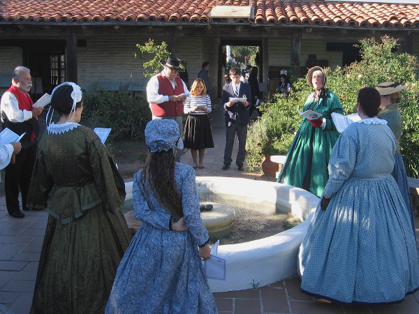Singing traditional Christmas carols around the old fountain in the outdoor courtyard of Casa de Estudillo.