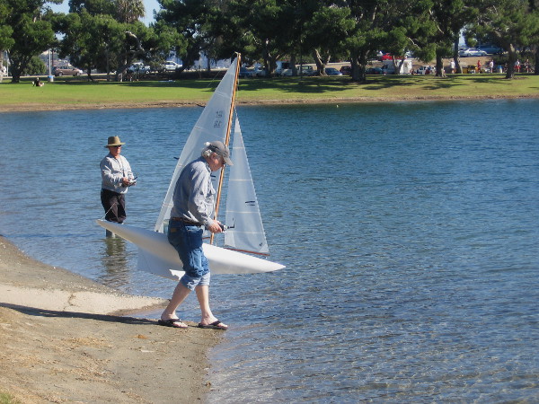 Member of the San Diego Argonauts gets ready to place a small sailboat into Vacation Isle's model yacht pond.