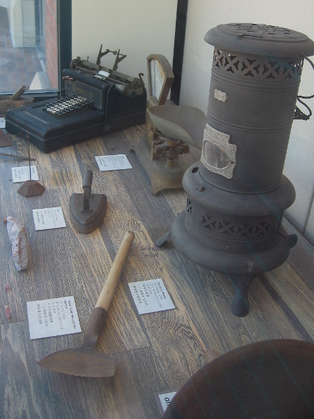 Items from daily life in old Chinatown include kerosene heater, iron, scale and soup spoon.