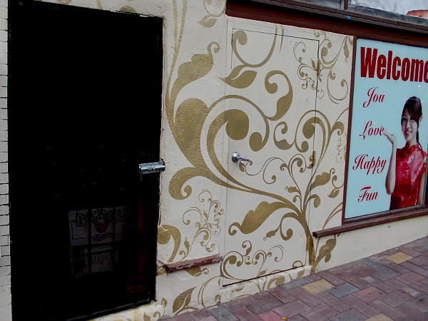 A door that might tempt people walking down the sidewalk. A nearby sign reads WELCOME You Love Happy Fun.