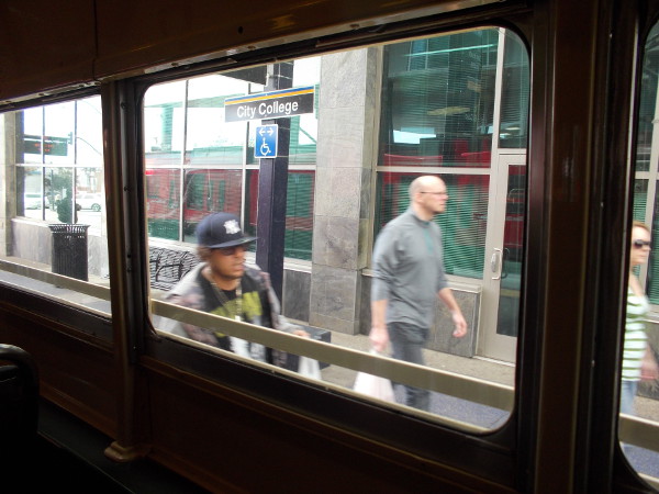 Looking out the vintage trolley window at people walking through the City College station.