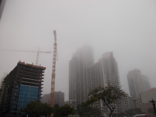 Cranes and construction next to several high towers, in a San Diego fog.
