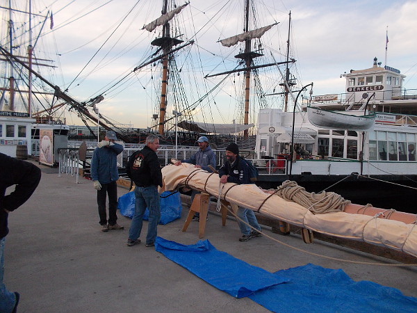 Museum volunteers gather around a ship's yard, which would soon be lifted by crane onto the nearly-completed Spanish galleon replica San Salvador.