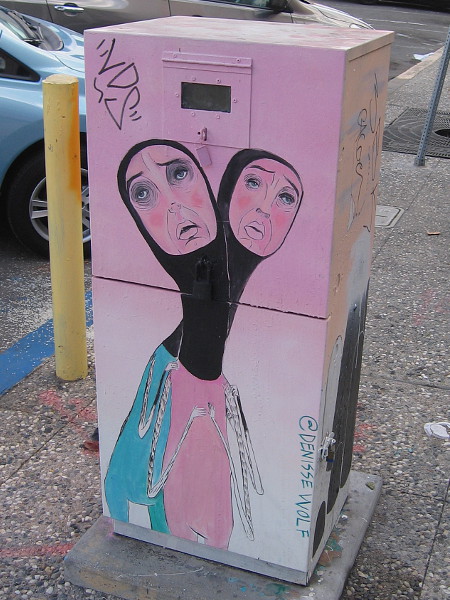 Two faces rise from one neck in this unusual utility box street art.