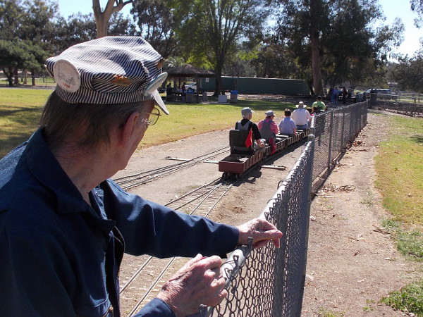 A "live steam" enthusiast watches folks ride a small train through Rohr Park, in San Diego's South Bay.