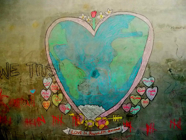 And young people created this chalk drawing on a playground wall. A heart encompasses the Earth and a puppy dog. Love is powerful.